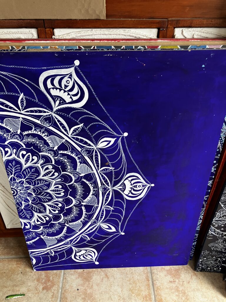 bois aggloméré 60x80 acrylique+posca : planche sur fond acrylique bleu avec des dessins mandala
